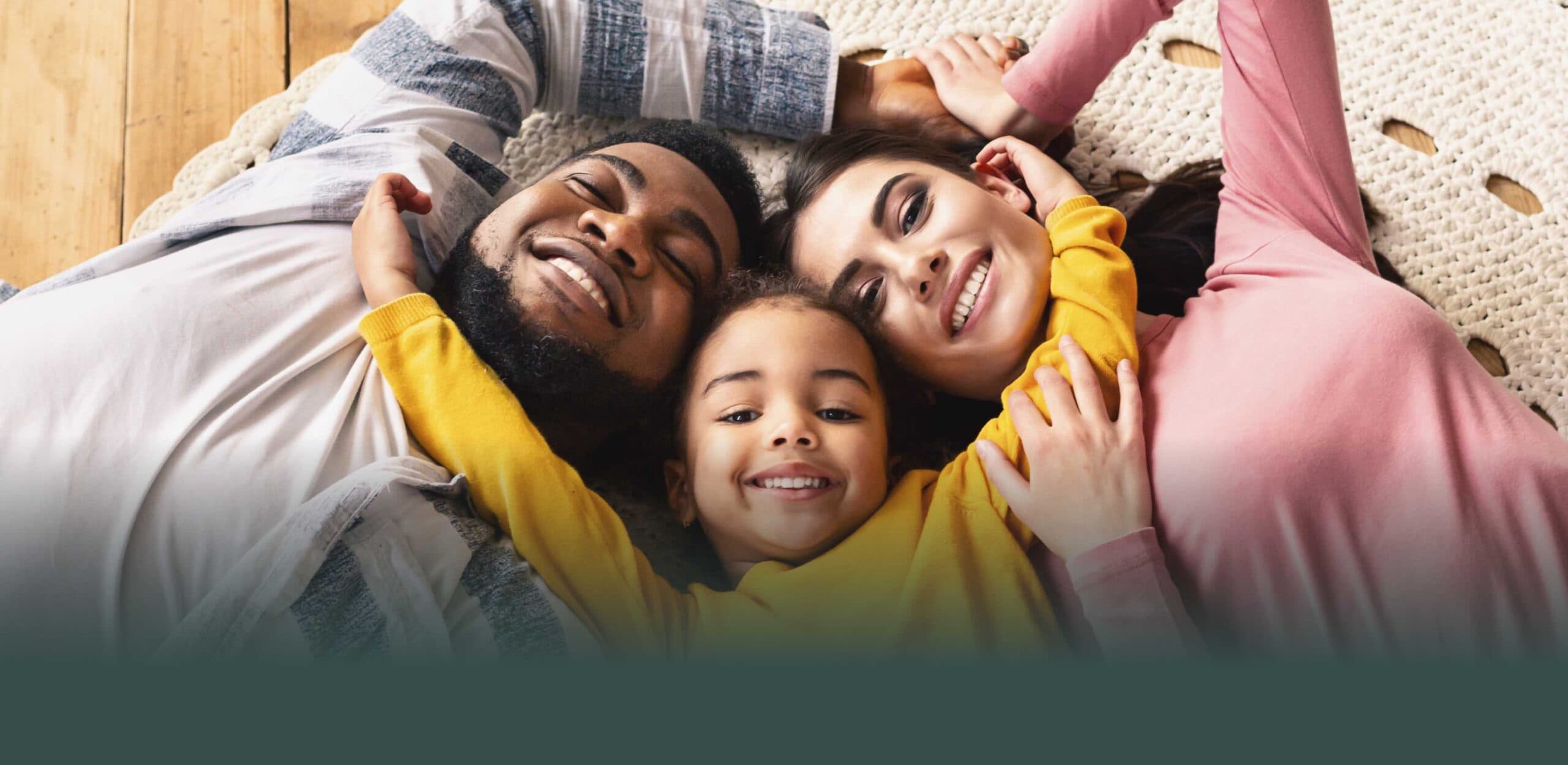 A smiling family lying together on a rug